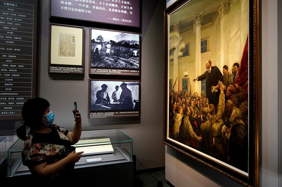 A woman takes a picture of Lenin in a painting at the Memorial of the First National Congress of the Communist Party of China in Shanghai, China, 4 June 2021. (Aly Song/Reuters)