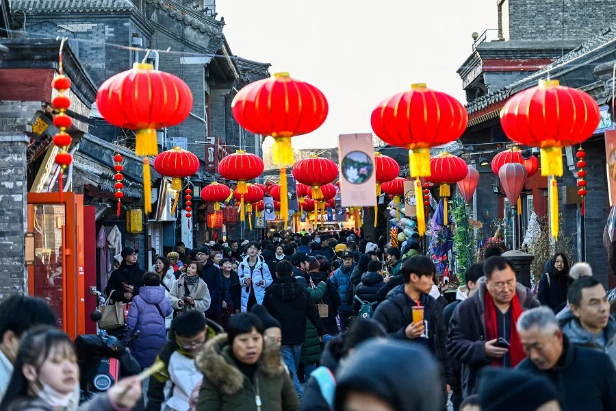 People walk along a street festively decorated at the Qianhai Lake tourist area in Beijing, China, on 7 February 2024. (Pedro Pardo/AFP)