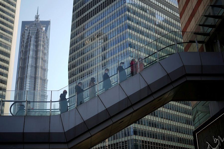 People ride an escalator on an overpass in Lujiazui financial district of Pudong, in Shanghai, China, 24 February 2022. (Aly Song/File Photo/Reuters)