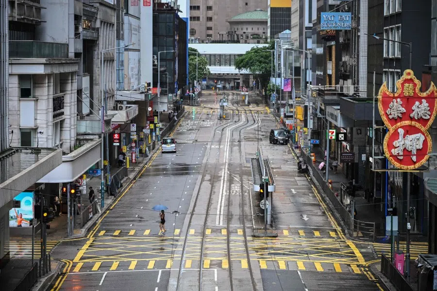 A woman crosses an empty street in the Central district as Typhoon Wipha moves towards Hong Kong on 20 July 2025.