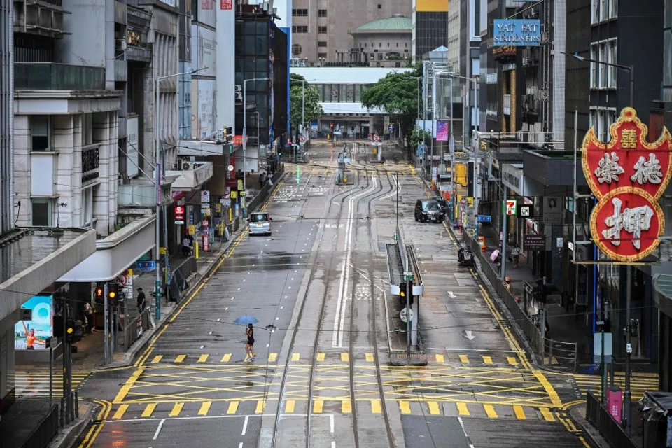 A woman crosses an empty street in the Central district as Typhoon Wipha moves towards Hong Kong on 20 July 2025. (Peter Parks/AFP)