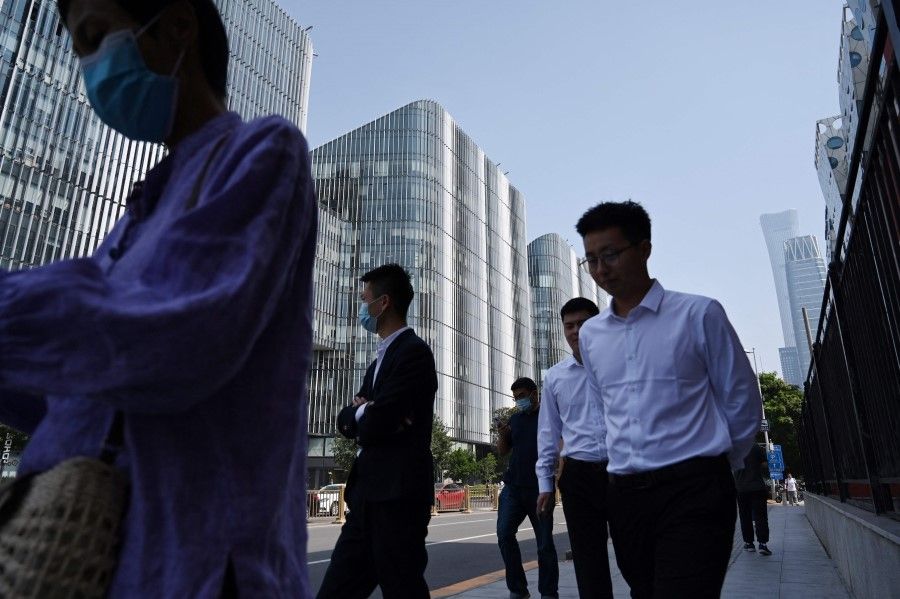 Office workers walk past buildings in Beijing's central business district on 8 September 2021. (Greg Baker/AFP)