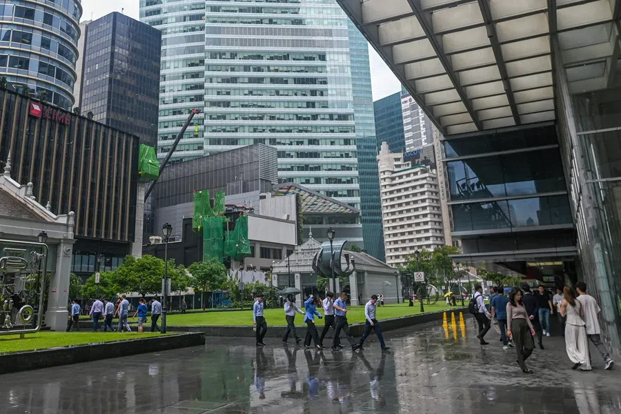 People walk outside office buildings in the financial district of Raffles Place in Singapore on 22 May 2025. (Roslan Rahman/AFP)