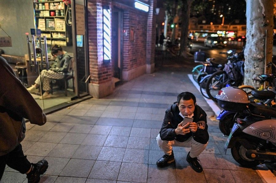 A man looks at his phone on a street in the Jing'an district in Shanghai, China, on 3 November 2022. (Hector Retamal/AFP)