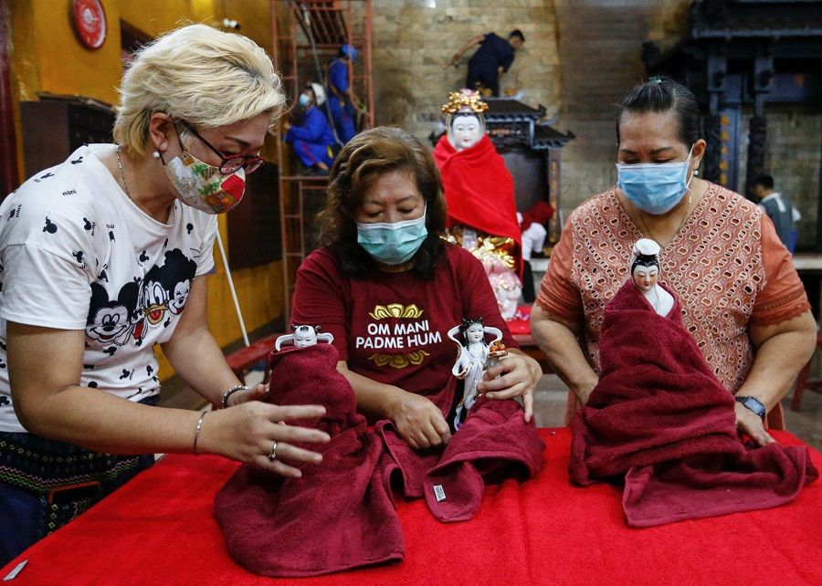 Women wearing protective face masks wipe religious figurines ahead of the Lunar New Year celebrations, at a temple in Jakarta, Indonesia, 4 February 2021. (Ajeng Dinar Ulfiana/Reuters)