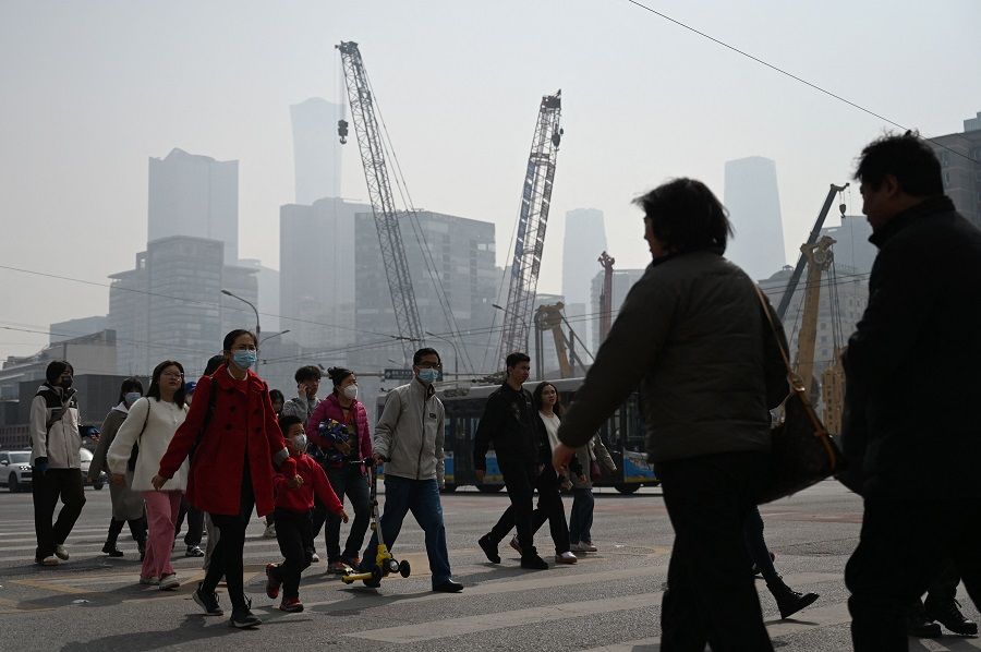 People cross a road in Beijing, China, on 16 March 2024. (Greg Baker/AFP)