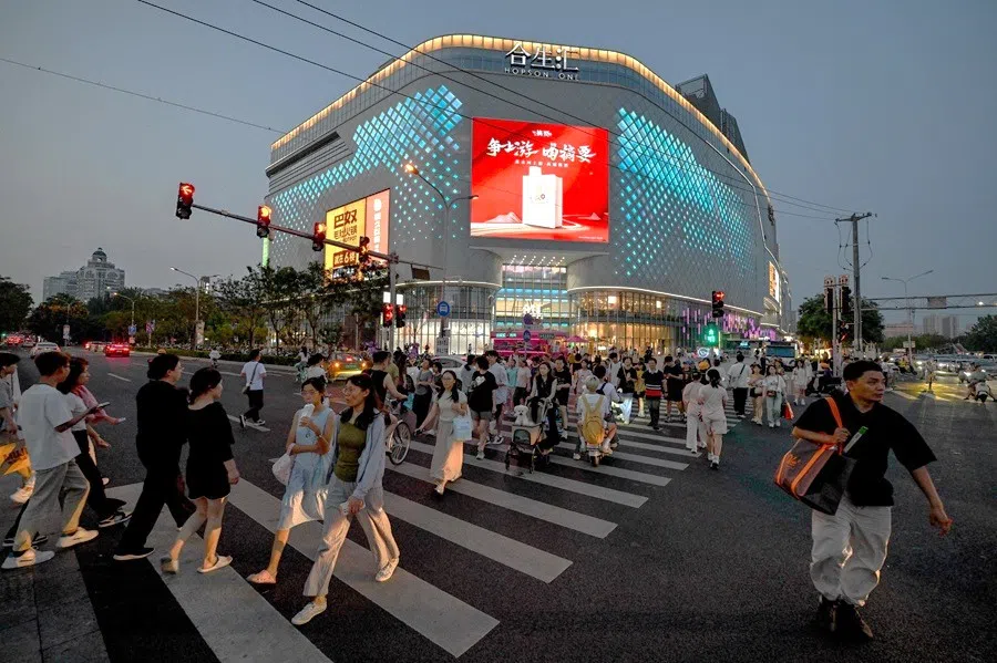 People cross a road outside a shopping mall in Beijing, China, on 1 July 2025. (Adek Berry/AFP)