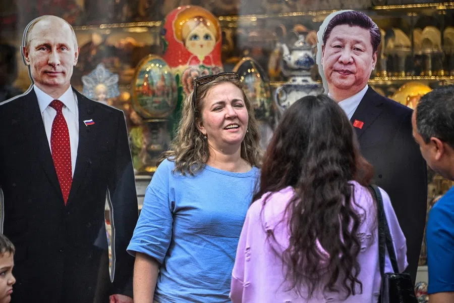 Tourist stand next to cardboard images depicting Chinese President Xi Jinping (right) and his Russian counterpart Vladimir Putin (left) at the touristic Arbat street in downtown Moscow on 22 July 2024.