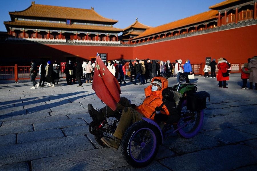 A man rides his tricycle past the Forbidden City in Beijing, China, on 23 January 2023. (Wang Zhao/AFP)