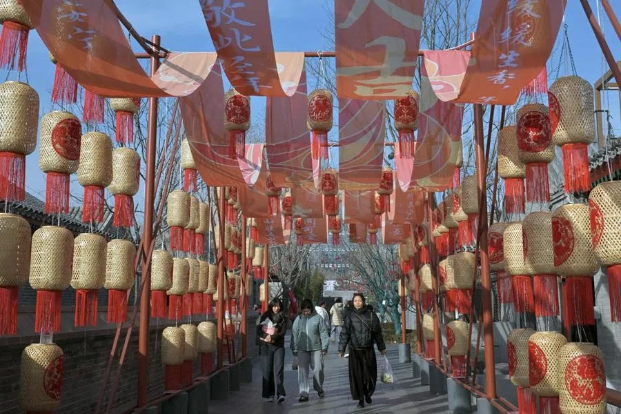 People walk past decorative lanterns at the Zhonghai Daji Alley shopping centre in Beijing on 3 February 2026. (Adek Berry/AFP)