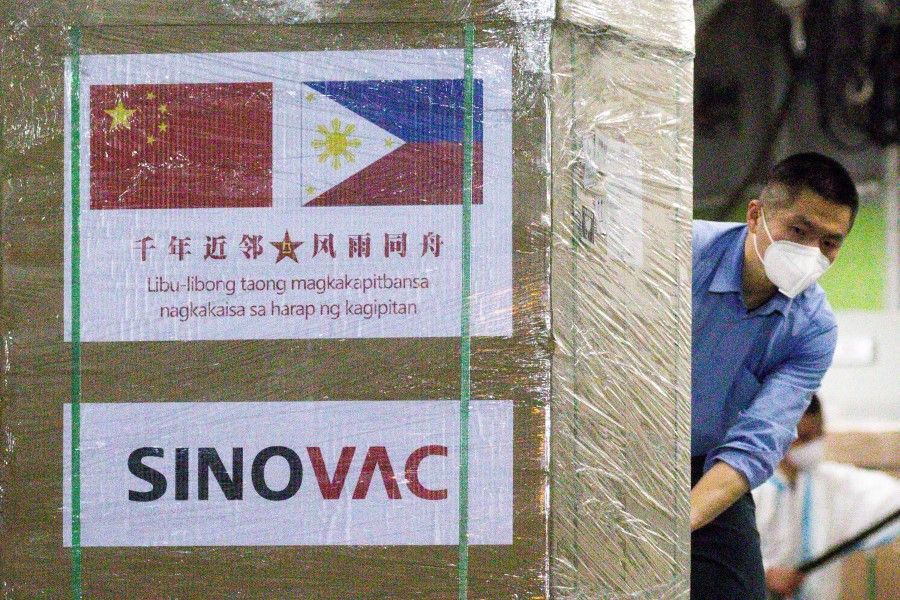 A worker unloads a box of Sinovac Biotech's CoronaVac vaccines against the coronavirus disease (Covid-19) from a Chinese military aircraft at Villamor Air Base in Pasay, Metro Manila, Philippines, 28 February 2021. (Eloisa Lopez/Reuters)
