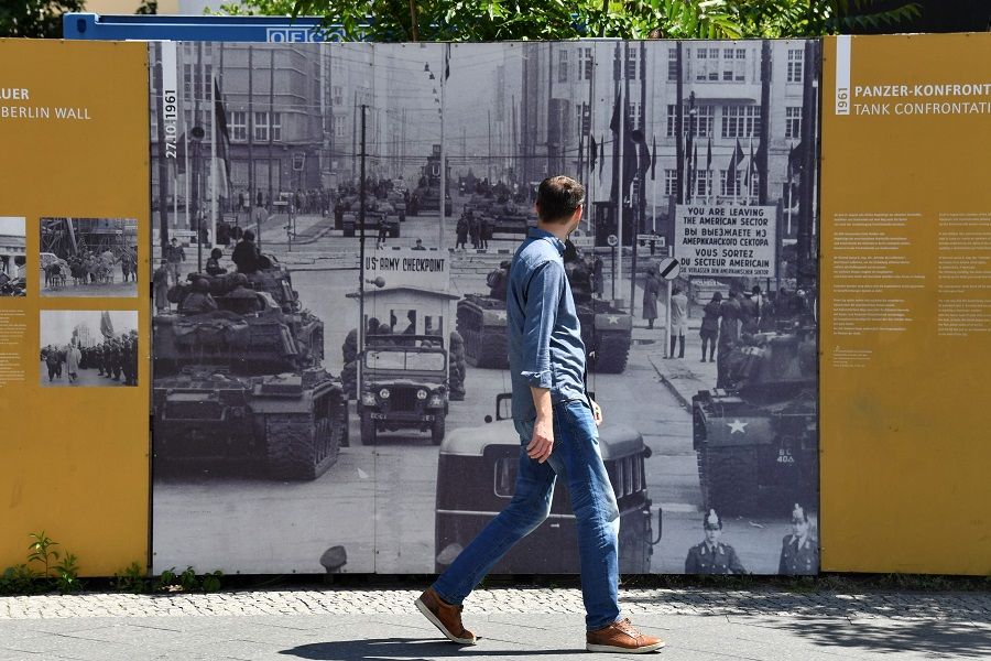 A man walks past a board displayed at Checkpoint Charlie landmark, a border crossing point between East and West Berlin during the Cold War, on 22 June 2020 in Berlin. (John Macdougall/AFP)