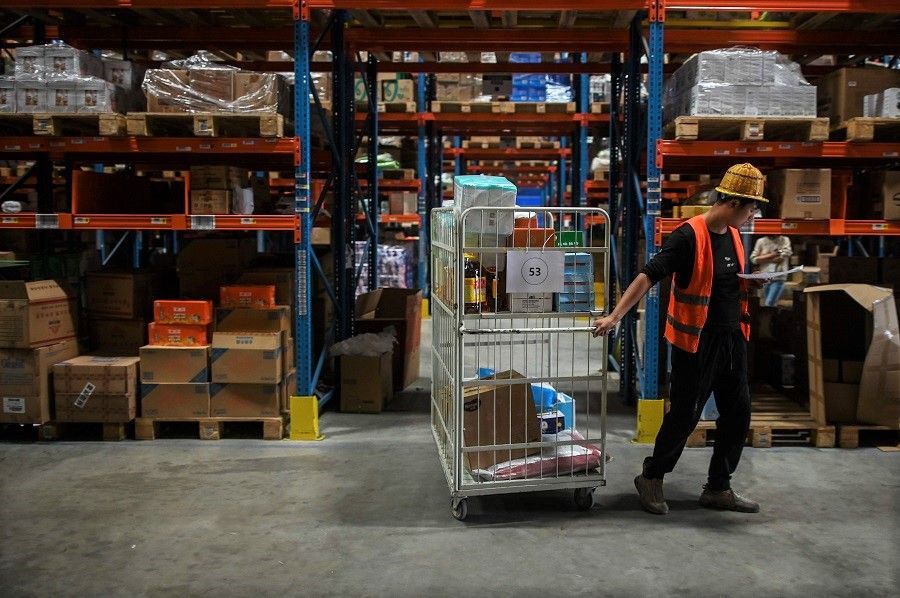 In this picture taken on 6 November 2020, an employee works in the warehouse of Cainiao Smart Logistics Network, the logistics affiliate of e-commerce giant Alibaba, in Wuxi, Jiangsu province, China, ahead of the Singles' Day sales. (Hector Retamal/AFP)