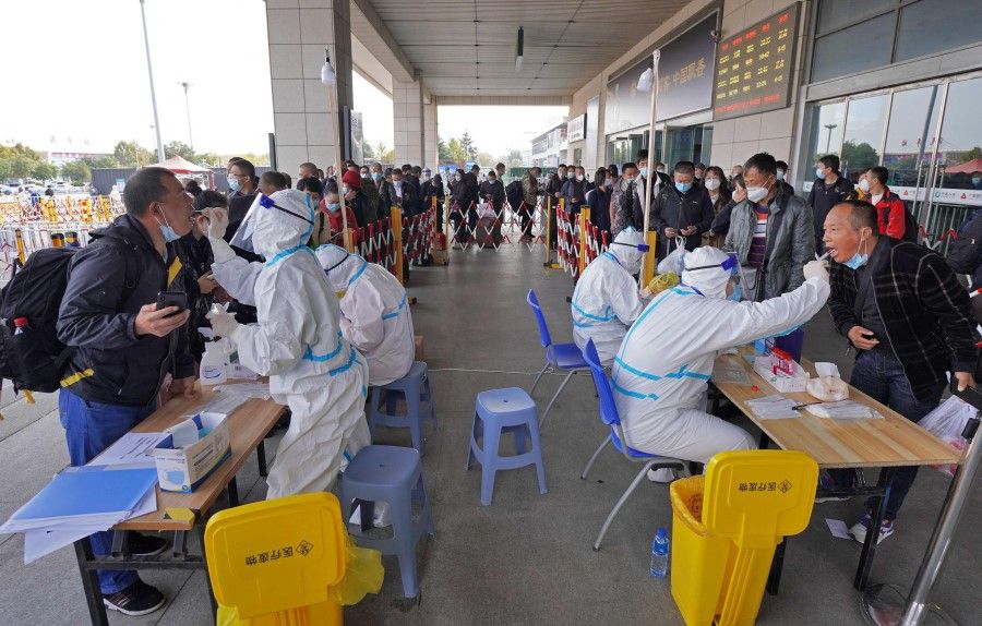 Health workers conduct Covid-19 coronavirus tests on travellers at the exit of Yantai Railway Station in China's eastern Shandong province on 2 November 2021. (AFP)
