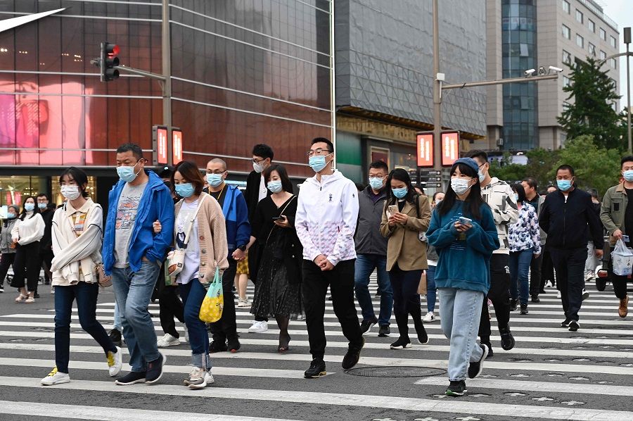 People walk on a pedestrian crossing in Beijing, China, on 5 October 2021. (Jade Gao/AFP)