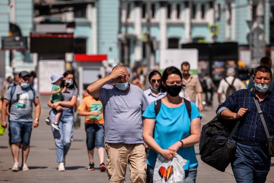 People wearing face masks walk down a street in Moscow on 21 June 2021. (Dimitar Dilkoff/AFP)