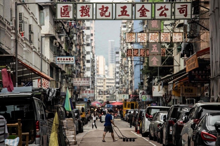 A man pushes a trolley across a street in the Kowloon district of Hong Kong on 22 November 2022. (Isaac Lawrence/AFP)