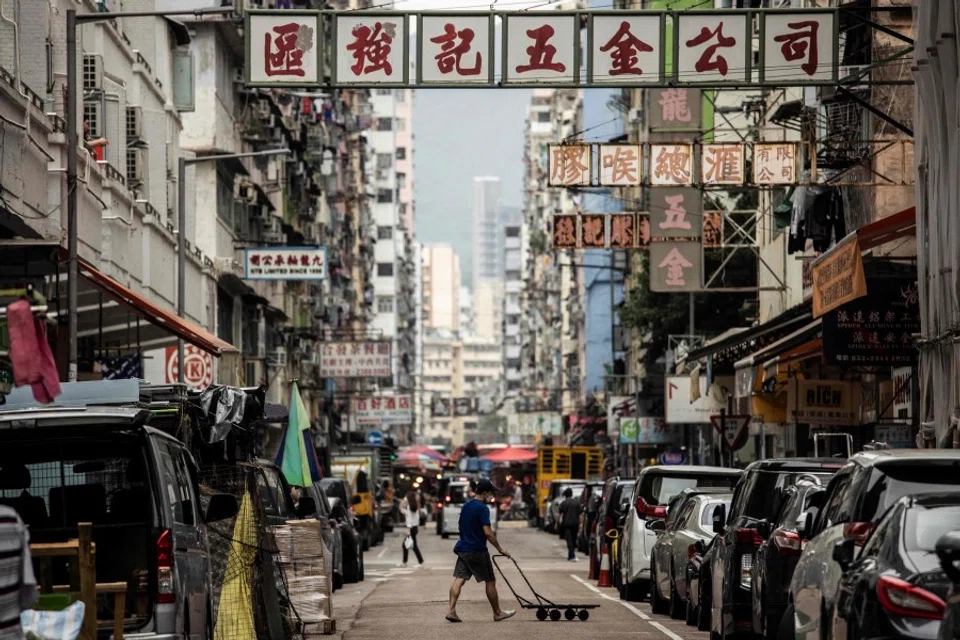 A man pushes a trolley across a street in the Kowloon district of Hong Kong on 22 November 2022. (Isaac Lawrence/AFP)