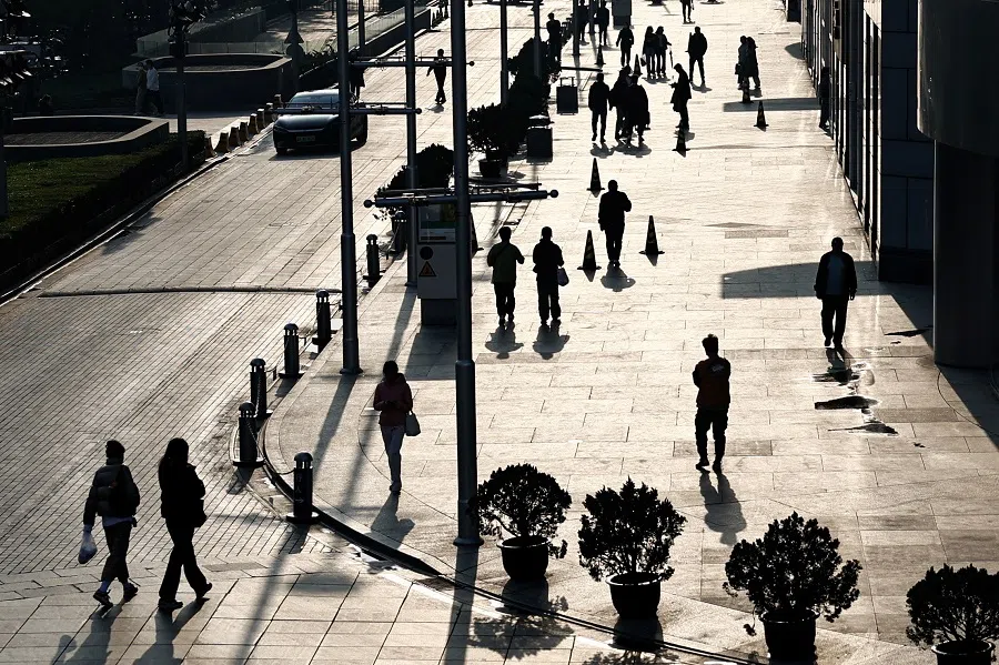 People walk past an office and shopping complex in Beijing, China, on 10 April 2024. (Tingshu Wang/Reuters)