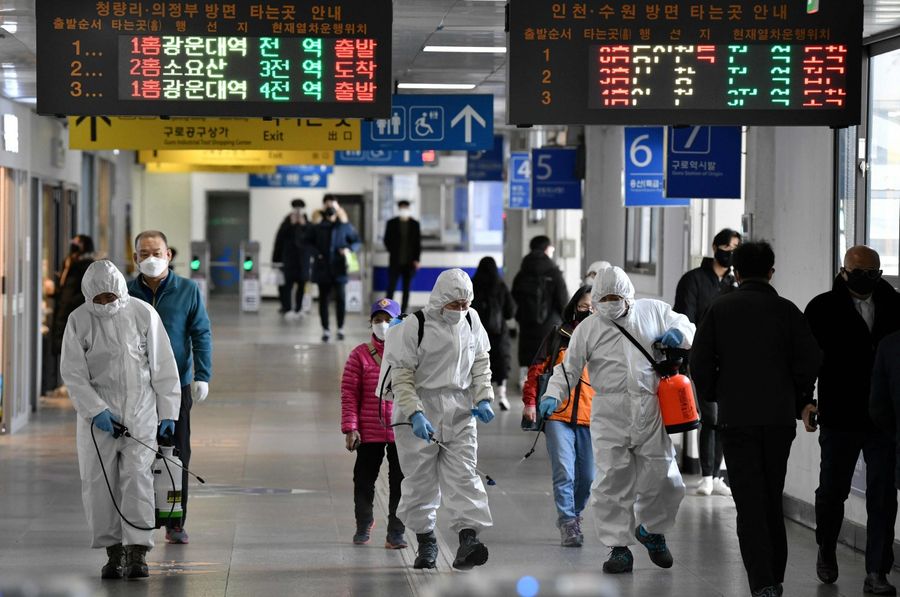 Workers wearing protective gear spray disinfectants to help prevent the spread of the Covid-19 coronavirus, at a subway station in Seoul on 13 March 2020. (Jung Yeon-je/AFP)