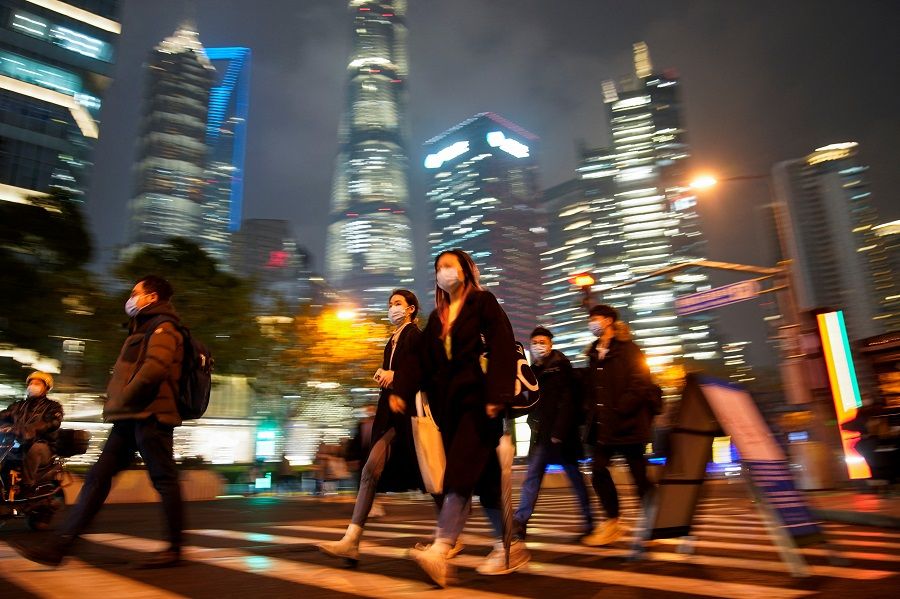 People wearing protective masks walk on a street, in Shanghai, China, 16 December 2021. (Aly Song/Reuters)