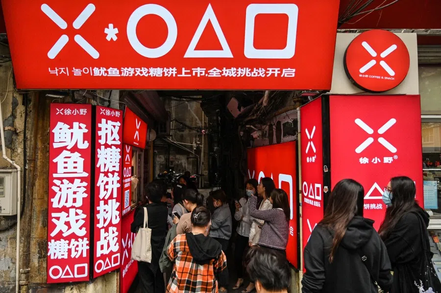 This photo taken on 12 October 2021 shows customers waiting at a small shop for dalgonas, a crisp sugar candy featured in the Netflix series Squid Game, in Shanghai. (Hector Retamal/AFP)