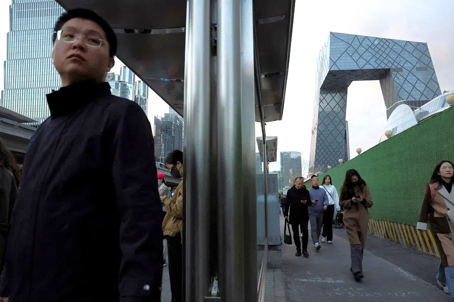 Commuters wait at a bus stop at the central business district in Beijing, China, 27 March 2025. (Florence Lo/Reuters)