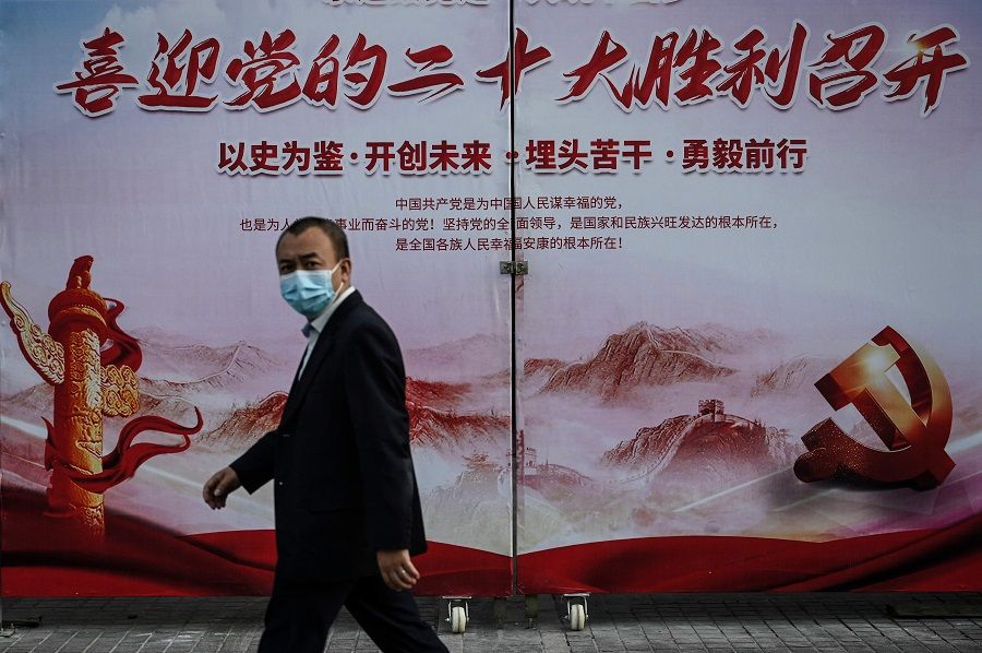 A man walks past a propaganda poster welcoming the 20th Party Congress, along a street in Beijing, China, on 21 September 2022. (Jade Gao/AFP)