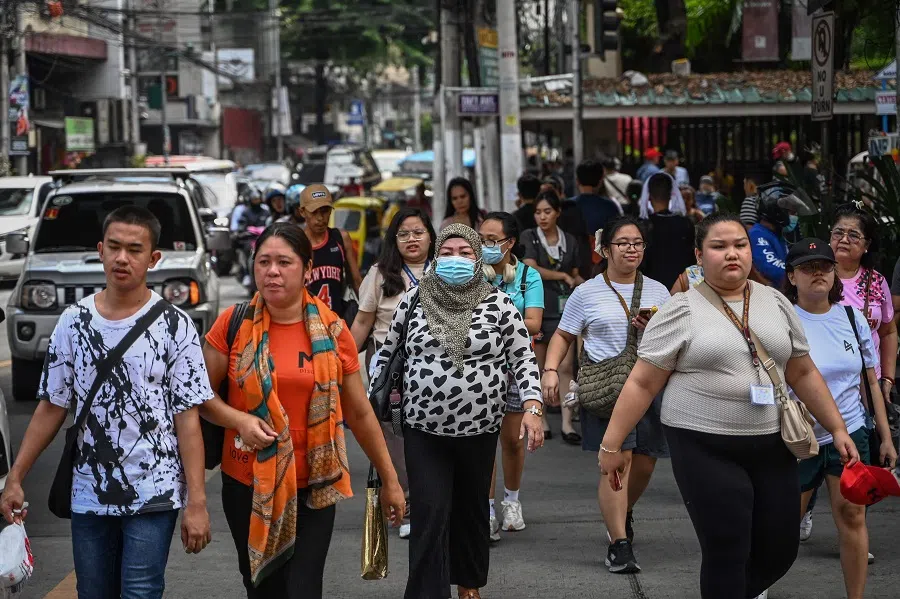 People cross the street in Manila, Philippines, 21 August 2024. (Jam Sta Rosa/AFP)