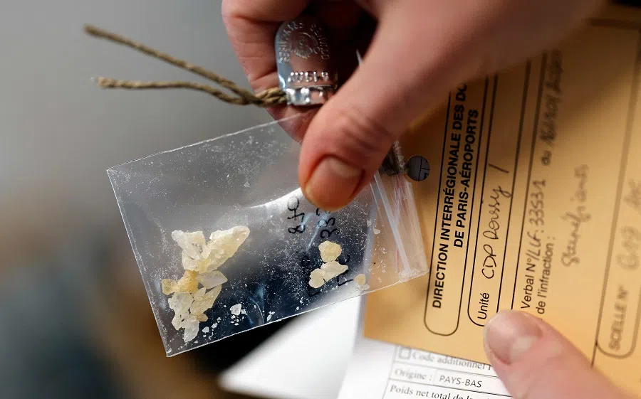 A lab technician shows a bag of drugs sent by customs and seized at the Paris Roissy Charles de Gaulle airport, to be analysed by chemical engineers from the central customs laboratory in Massy, southern Paris, on 12 November 2020. (Thomas Coex/AFP)