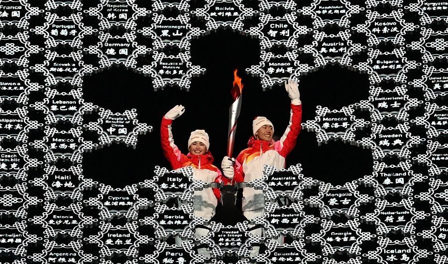 Chinese torchbearer athletes Dinigeer Yilamujian (left) and Zhao Jiawen wave with the Olympic flame in the middle of a giant snowflake during the opening ceremony of the Beijing 2022 Winter Olympic Games, at the National Stadium, known as the Bird's Nest, in Beijing, China, on 4 February 2022. (Manan Vatsyayana/AFP)