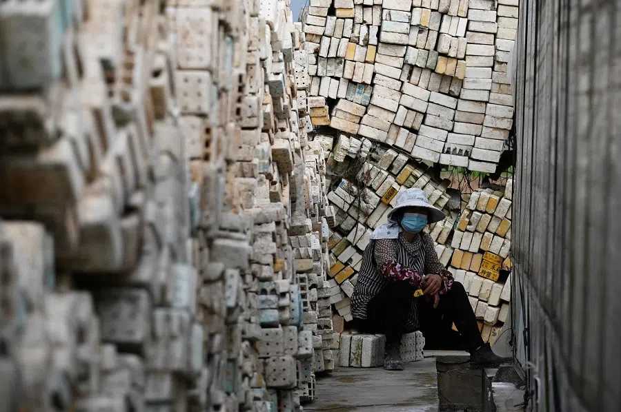 This photo taken on 30 March 2025 shows a farmer resting beside trays used for growing tobacco seedlings in a village in Yuxi, Yunnan province, China.