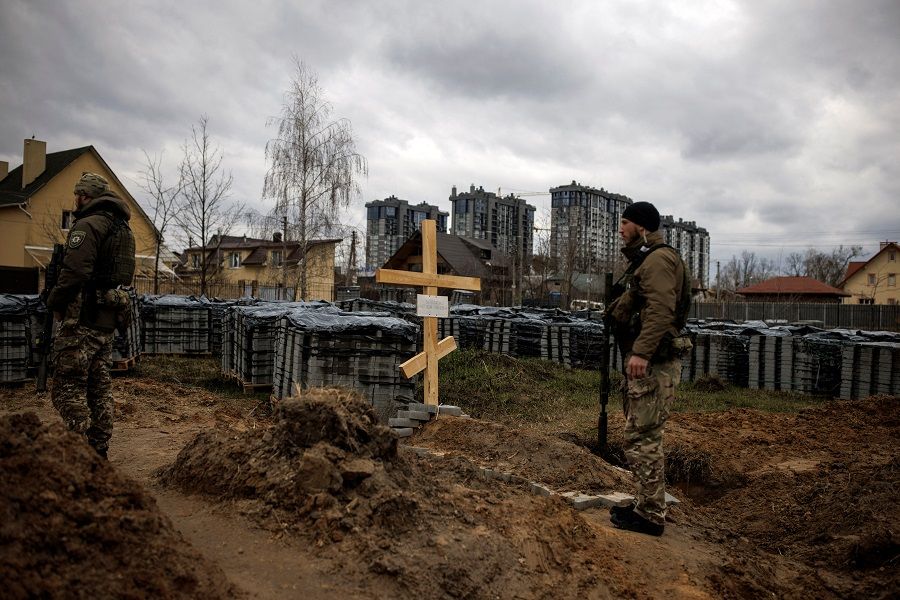 Ukrainian soldiers stand next to the grave of a civilian, who according to residents was killed by Russian soldiers, amid Russia's invasion of Ukraine, in Bucha, Kyiv region, Ukraine, 6 April 2022. (Alkis Konstantinidis/Reuters)
