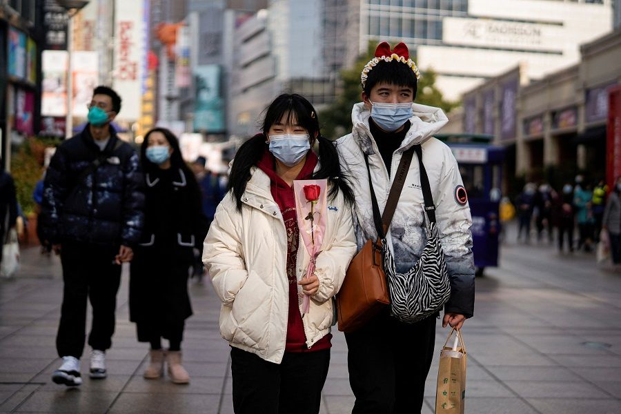 A couple wearing protective masks walks on a street in Shanghai, China, on 14 February 2022. (Aly Song/Reuters)