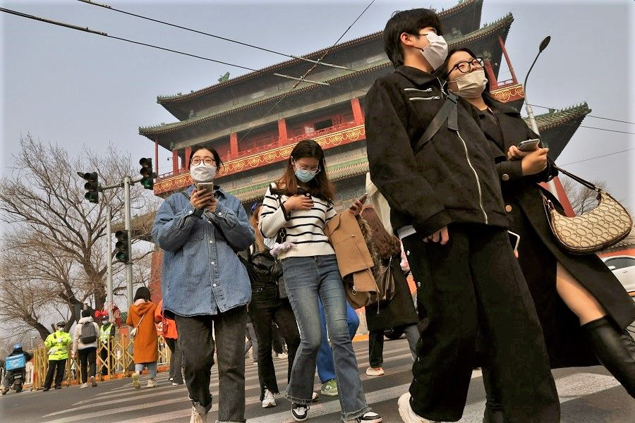 People walk past the Drum Tower in Beijing, China, 5 March 2023. (Tingshu Wang/Reuters)