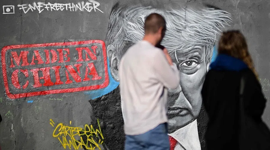 Visitors walk past a mural by Berlin-based graffitti artist Eme Freethinker of US President Donald Trump and the lettering reading ‘Made in China’ on a wall at the Mauerpark public park in Berlin, Germany, on 26 April 2025.