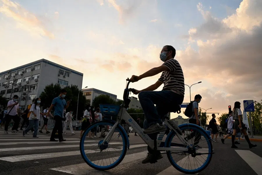 This photo taken on 16 August 2022 shows people crossing a street in Beijing. (Noel Celis/AFP)