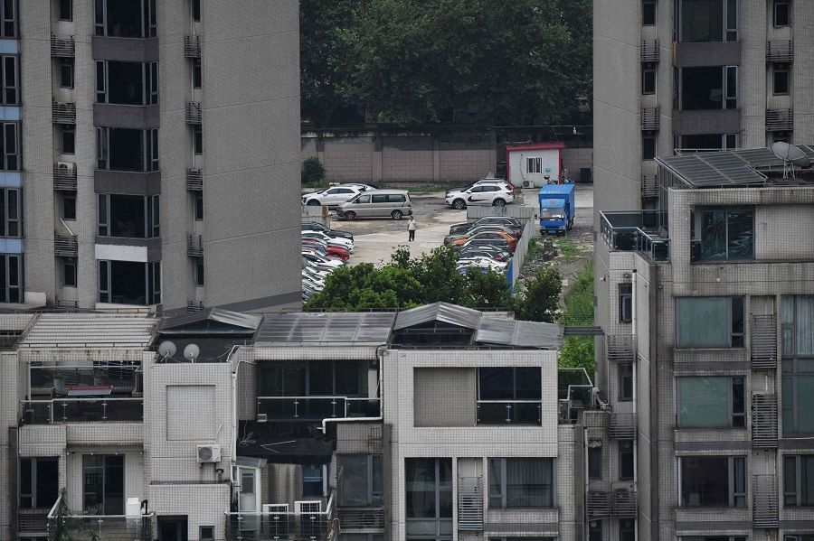 A security guard walks in a car park behind residential buildings in Shanghai, China, on 16 August 2021. (Greg Baker/AFP)