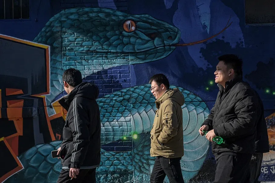 People walk past a snake graffiti in Beijing on 14 January 2025.  (Jade Gao/AFP)