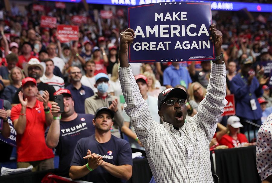 A supporter of US President Donald Trump holds up a "Make America Great Again" sign as the president arrives at his first re-election campaign rally in several months in the midst of the coronavirus outbreak, at the BOK Center in Tulsa, Oklahoma, US, on 20 June 2020. (Leah Millis/Reuters)
