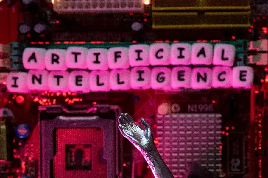 AI (Artificial Intelligence) letters and a robot hand are placed on a computer motherboard in this illustration taken on 23 June 2023. (Dado Ruvic/Illustration/Reuters)