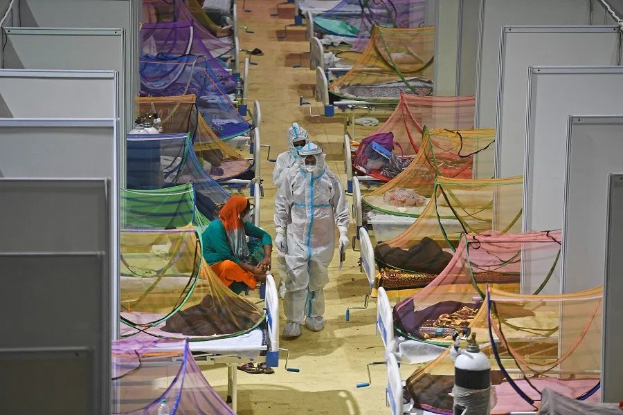 Health workers wearing personal protective equipment (PPE) suits attend to Covid-19 coronavirus patients inside a centre of the Commonwealth Games (CWG) village temporarily converted into a Covid care facility, in New Delhi, India on 2 May 2021. (Tauseef Mustafa/AFP)