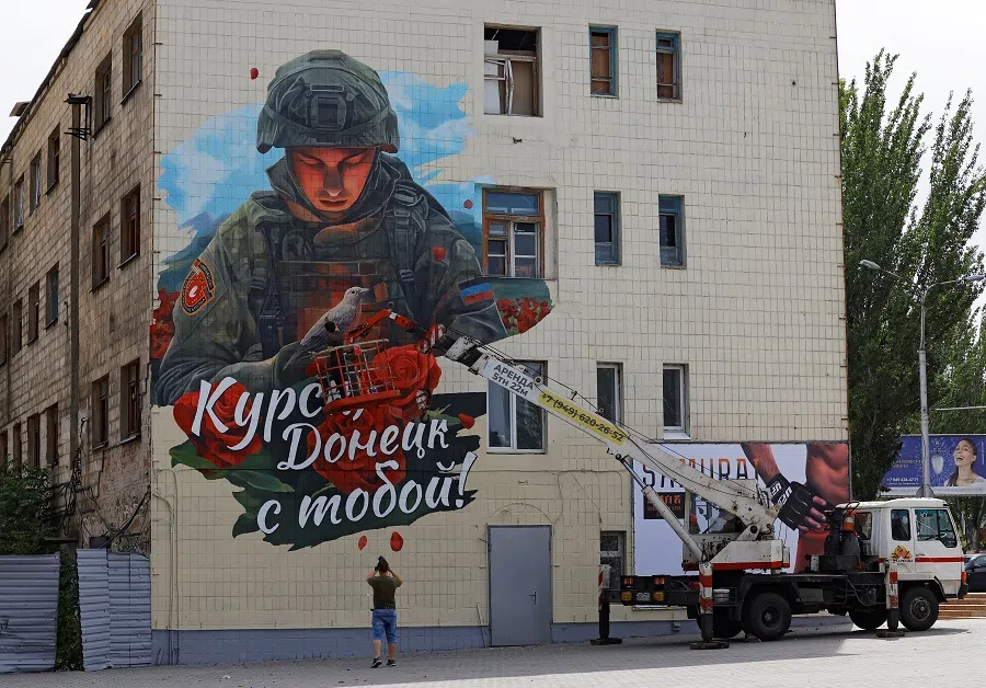 Painter Vladislav Stepnoi works on his mural reading “Kursk, Donetsk is with you!” in support of residents of Russia’s Kursk region in the course of Russia-Ukraine conflict, on the facade of a building in Donetsk, Russian-controlled Ukraine, 31 August 2024. (Alexander Ermochenko/Reuters)