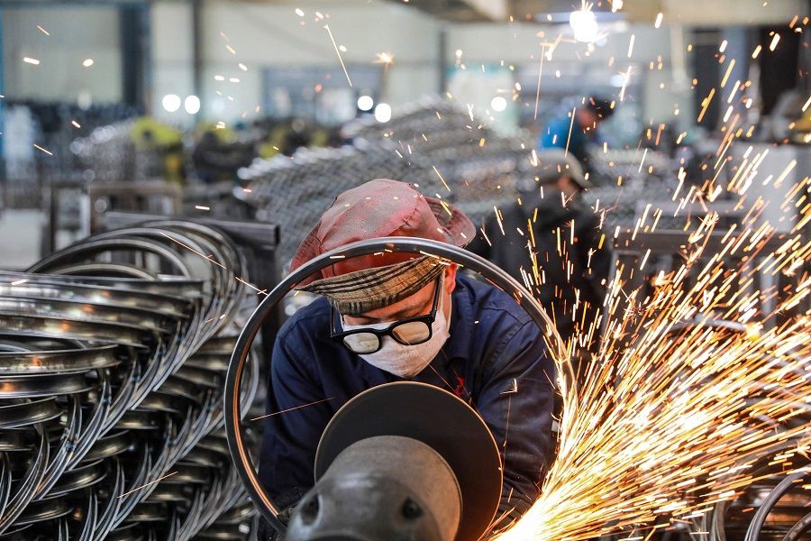 A worker welds wheels at a factory in Hangzhou, Zhejiang province, China on 16 April 2021. (STR/AFP)