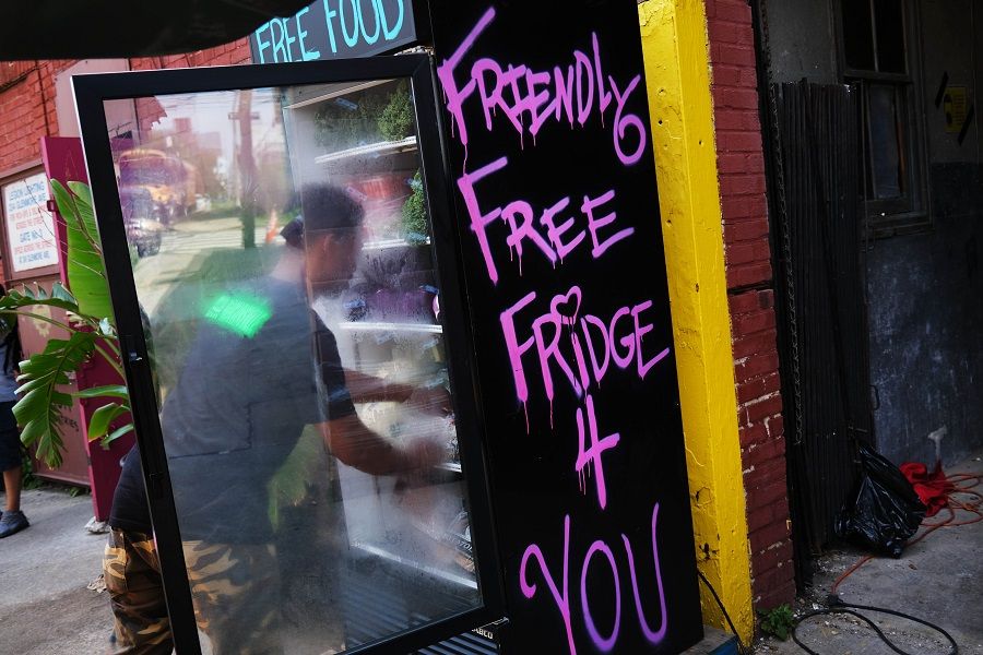 A member of Universe City, a decentralised food hub in the Brownsville neighborhood that is working to build food sovereignty while also promoting community healing practices, restocks an outside refrigerator that lets members of the community pick up fresh food for free on 22 July 2020 in the Brooklyn borough of New York City. (Spencer Platt/Getty Images/AFP)