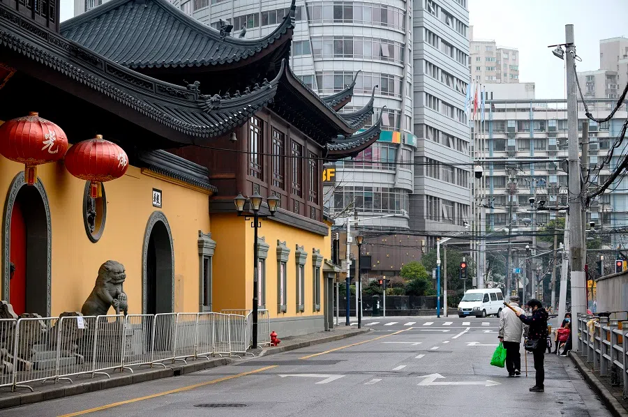 A woman wearing a protective face mask offers prayers outside the closed Jade Buddha Temple in Shanghai on 14 February 2020. (Noel Celis/AFP)