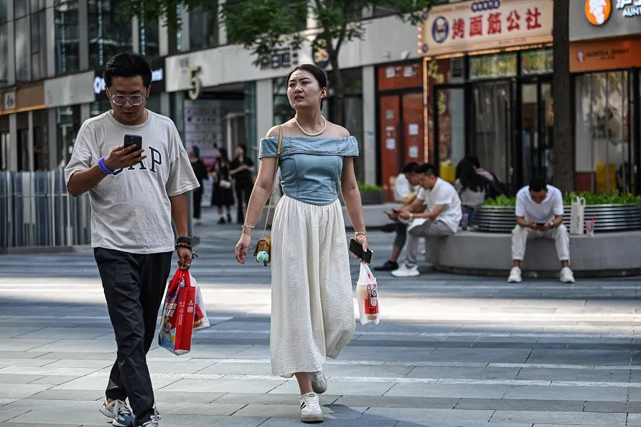 This photo taken on 29 August 2024 shows people outside an office building in Beijing. (Jade Gao/AFP)