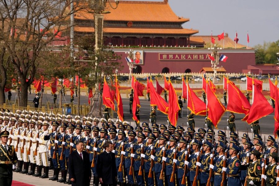 French President Emmanuel Macron inspects an honour guard with Chinese President Xi Jinping outside the Great Hall of the People with the portrait of Mao Zedong on Tiananmen Gate in the background in Beijing, 6 April 2023. (Ng Han Guan/Pool via Reuters)