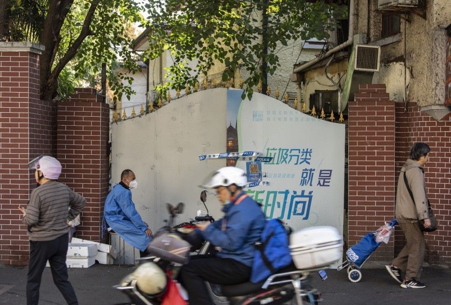 A worker in protective gear guards an entrance to a neighbourhood placed under lockdown due to Covid-19 in Shanghai, China, on 7 November 2022. (Qilai Shen/Bloomberg)