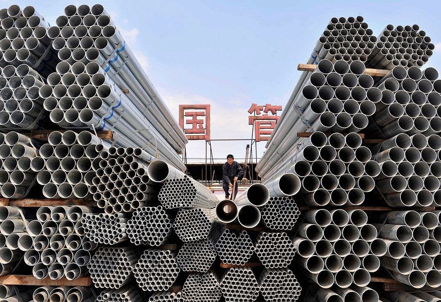 A labourer piles up steel pipes at a steel and iron factory in Shenyang, Liaoning province, China, 23 April 2010. (Sheng Li/File Photo/Reuters)